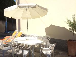 a white table and chairs with an umbrella at Casa Lorenzo in Bellagio