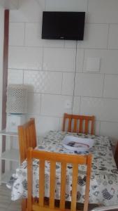 mesa de comedor con 2 sillas y TV en Residencial Lena a 300 metros da praia, en Florianópolis