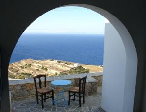 an archway with a table and two chairs and the ocean at Belvedere Apartments in Chora Folegandros