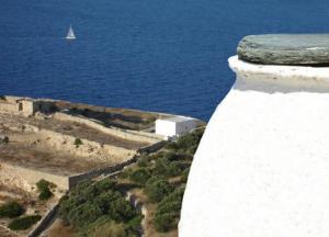 a white wall with a sail boat in the water at Belvedere Apartments in Chora Folegandros