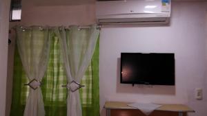 a living room with a television and green curtains at Pousada Brenda in Fortaleza