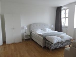 ein weißes Schlafzimmer mit einem Bett und einem Fenster in der Unterkunft Historisches Bürgerhaus Dresden -Kulturstiftung- in Dresden