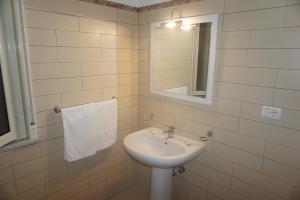 un bagno bianco con lavandino e specchio di Hotel Villa Souvenir a Forza dʼAgro Altre 16 foto