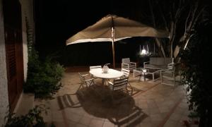 a table and chairs with an umbrella at night at Casa Giummarra in San Vito lo Capo