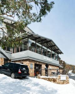 una macchina nera parcheggiata di fronte a un edificio di The Denman Hotel in Thredbo a Thredbo