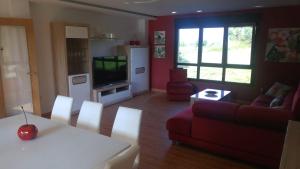 a living room with a red couch and a tv at Casa A Veiga in O Grove +30 photos