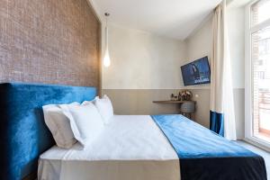 een slaapkamer met een blauw en wit bed en een raam bij A World Aparts - Barberini Boutique Hotel in Rome