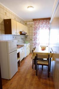 a kitchen with a table and a white refrigerator at Appartamenti Padoan in Sottomarina