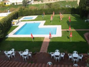 una piscina con mesas y sombrillas junto a en Hotel Hostal del Sol en Sant Feliu de Guixols