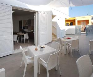 une salle à manger avec des tables et des chaises blanches dans l'établissement Sole del Sud, à Torre San Giovanni