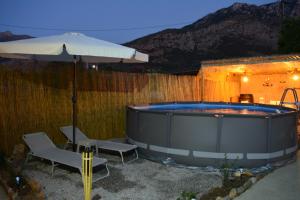 a hot tub with two chairs and an umbrella at Elias Maro House in Avdou