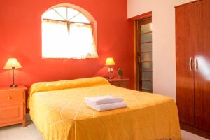 a bedroom with a yellow bed with two towels on it at Hostal Alamo in Cafayate