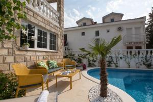 a patio with a pool and chairs and a palm tree at Apartments Captain's Villa in Budva