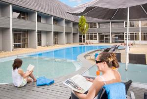 a woman and a child sitting on a deck by a swimming pool at Apollo Hotel Rotorua in Rotorua