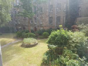 グラスゴーにあるBentinck Street Ground Floor Apartmentの大きなレンガ造りの建物の前の庭園