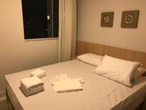 a bed with white sheets and towels on it at Apartamento tipo Flat para temporada em Caldas Novas com cozinha in Caldas Novas