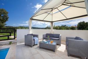 a patio with two chairs and an umbrella at Holiday Home Sanchi in Labin