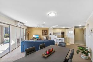 a living room and dining room with a blue couch at Rovera Apartments in Maroochydore