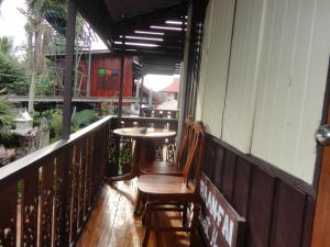 eine Veranda mit einem Tisch und Stühlen auf dem Balkon in der Unterkunft Baanfai Guesthouse Chiangkhong in Chiang Khong