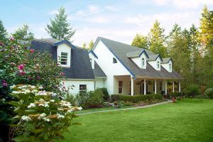 a large white house with a yard with flowers at The Inlet Bed & Breakfast in Saanichton