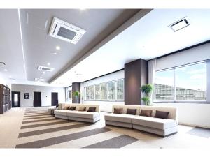 uma sala de estar com 2 sofás e janelas grandes em Y's Hotel Asahikawa Ekimae em Asahikawa