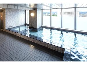 a large swimming pool in a building with windows at Y's Hotel Asahikawa Ekimae in Asahikawa