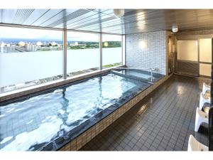 a large indoor swimming pool in a building with windows at Y's Hotel Asahikawa Ekimae in Asahikawa