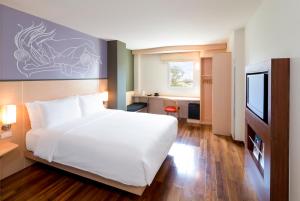 - une chambre avec un lit blanc et une télévision dans l'établissement ibis Vientiane Nam Phu, à Vientiane