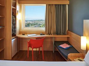 een kamer met een bureau, een stoel en een raam bij ibis Sorocaba in Sorocaba