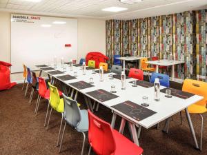 a conference room with a long table and colorful chairs at ibis Lincoln in Lincoln