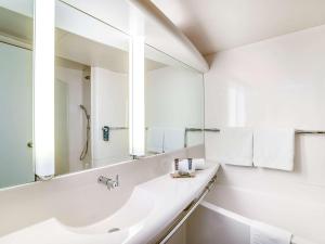 a bathroom with two sinks and a mirror at Novotel Paris Orly Rungis in Rungis