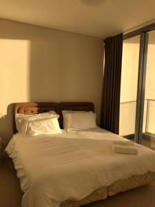 una camera da letto con un grande letto con lenzuola e cuscini bianchi di 2 bedroom high rise apartment a Sydney