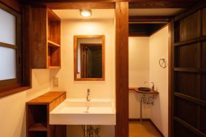 ein Bad mit einem Waschbecken und einem Spiegel in der Unterkunft 紀州湯浅古民家町屋宿泊 千山庵 SenzanAn かじやまち301 in Yuasa