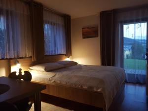 a bedroom with a bed and a table and windows at Pokoje Gościnne A.T. Mikołajczyk in Krościenko