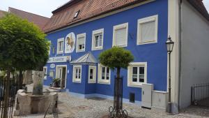 a blue and white building with a tree in front of it at Pension "Zum Raubritter" in Langquaid