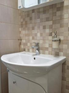 a white sink in a bathroom with a mirror at Horizon Apartment in Varna City +8 photos