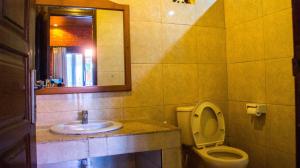 a bathroom with a toilet and a sink and a mirror at Leyeh Leyeh Homestay in Canggu