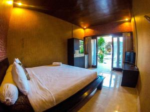 a bedroom with a large bed and a television at Leyeh Leyeh Homestay in Canggu