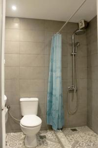 a bathroom with a toilet and a blue shower curtain at Kehagias Apartments in Nea Vrasna