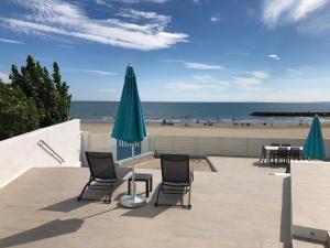 un patio avec des chaises et une table avec un parasol et la plage dans l'établissement La Vigie, au Grau-dʼAgde