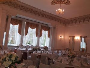 a dining room with tables and chairs in a room with windows at Agroturystyka "Pałac w Janowie" in Janów