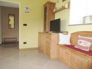 a room with a tv on a wooden cabinet with atainment at Casa Roberto - piano terra con giardino in Levico Terme