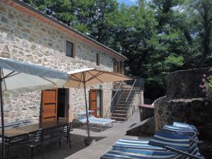 a patio with chairs and an umbrella and a building at Agriturismo Molino del Ponte in Arcidosso