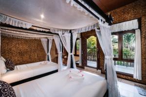 two beds in a room with windows at Bunda 7 Bungalows in Nusa Lembongan