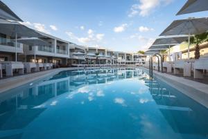 a swimming pool with chairs and umbrellas next to a hotel at Aloe Boutique Hotel & Suites - adults only in Almyrida