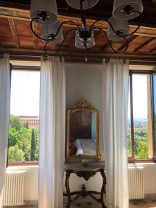 a bedroom with a mirror and a table in front of windows at BnB Paolina in Siena