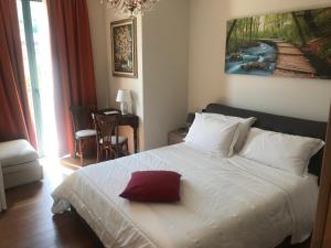 een slaapkamer met een wit bed met een rood kussen erop bij Locanda Al Bersò in Calco