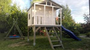 a tree house with a slide and swings at Domki Letniskowe Oaza Wicie in Wicie