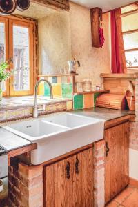 a kitchen with a large white sink and wooden cabinets at The Dragon Barn - Studio in Ascou