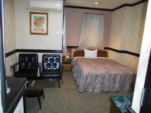 川口市にあるNishikawaguchi Station Hotel Stay Loungeのベッドと椅子付きのホテルルーム